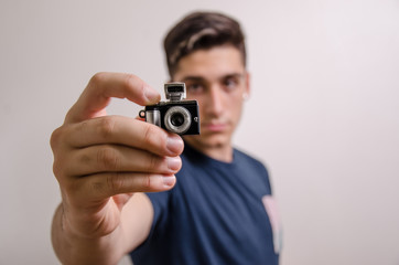 Young man with a miniature camera (focus on foreground)