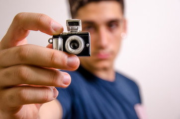Young man with a miniature camera (focus on foreground)