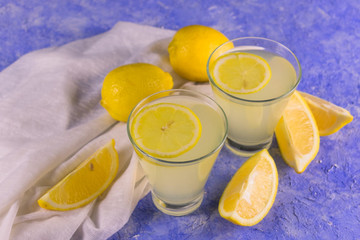 Refreshing lemonade and fresh lemons on a light blue background.