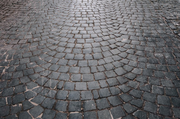The gray paving stones laid out in a semicircle. The texture of the old dark stone. Road surface....