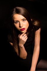 Portrait of a beautiful young woman in a black dress with a cool makeup and good skin. Studio, black background.