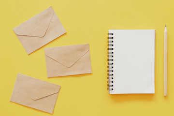 Brown paper envelope on yellow pastel abstract background.