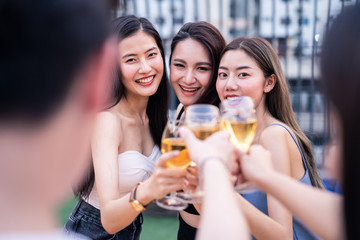 Group of young cute Asian girl gang best friends having party at rooftop restaurant. Girls drinking beer alcohol and toasting glass feeling happy enjoy, fun with smile face. Night lifestyle concept.