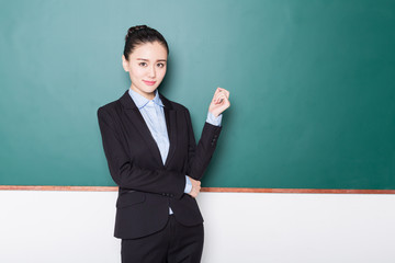 portrait of female teacher pointing to chalkboard.