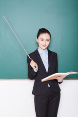 portrait of female teacher pointing to chalkboard.