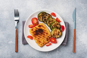 Schnitzel of chicken and zucchini cooked on the grill. Fresh tomatoes on a plate. Ready delicious dinner lunch.