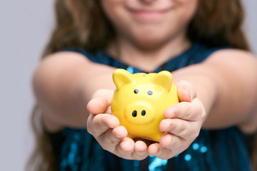 Fototapeta na wymiar Piggy bank at young girl hands. Smile female face. Yellow moneybox.