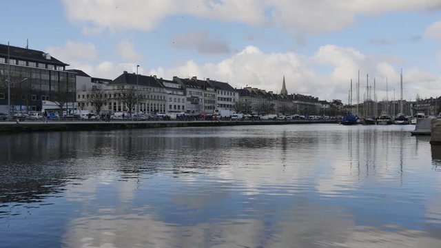 Time lapse in the city port in Caen, a town located in Normandie, northern France. Cloudy sky. Reflections on the water. Seabirds in the sky.