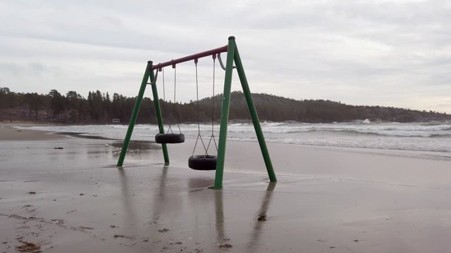 Swings moving slowly in the wind on a flooded beach