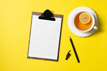 Background with an open Notepad for a business Breakfast or for writing recipes. Tea with lemon in a white Cup on a yellow background. The view from the top