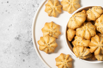 Lemon cookies with poppy seeds in a white ceramic bowl on the gray kitchen table. Shortbread. Space for text