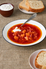 Vegetable beet soup with sour cream in a bowl on a brown background