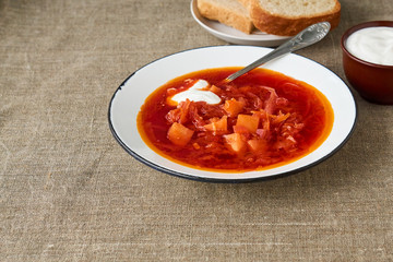 Vegetable beet soup with sour cream in a bowl on a brown background