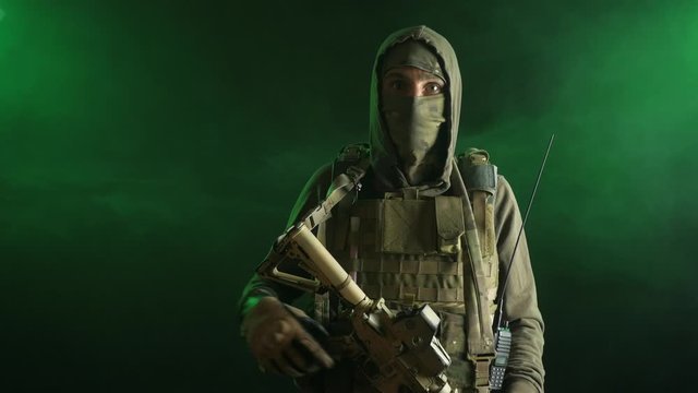 a saboteur soldier in military clothing with a weapon on a dark background removes a Balaclava
