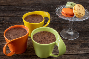 Many colorful macaroons on the table with coffee and hot chocolate