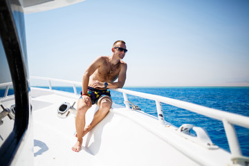 guy businessman in shorts and glasses on a white yacht in the red sea