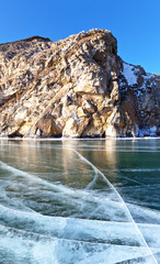 Baikal Lake in February sunny day. View on Shibeta mountain revered by locals. Beautiful winter landscape. Natural background of smooth blue ice with a cracks. Ice travel