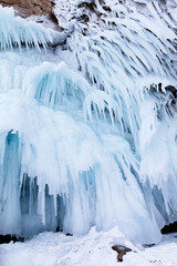 Lake Baikal in the winter. Unusual long icicles on the icy coastal cliffs of Olkhon Island. Natural cold background