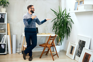 Attractive freelance male standing in office and showing empty copy space.