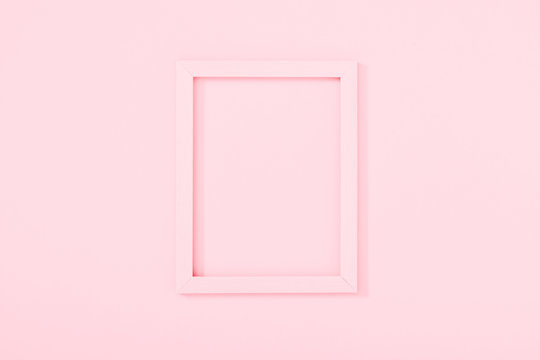 Empty pink photo frame on pastel pink background. Flat lay, top view, copy space