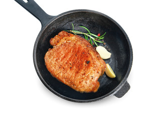 Frying pan with cooked pork steak on white background
