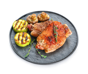 Plate with cooked pork steaks on white background