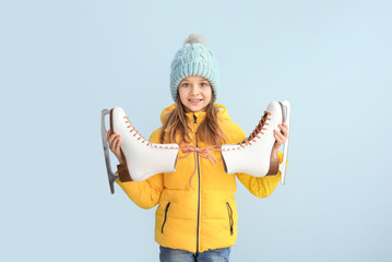 Fototapeta na wymiar Cute little girl with ice skates on light background