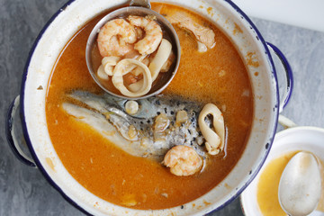 fish soup with salmon head and tom yam paste in big saucepan top view close up photo