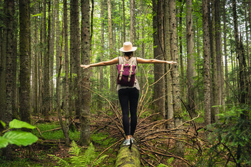 Woman in forest balancing on tree trunk.