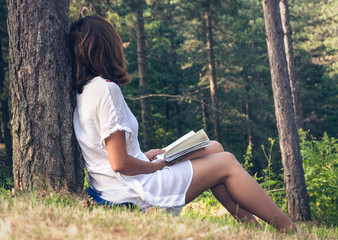 Beautiful woman reading book in nature in vacation.