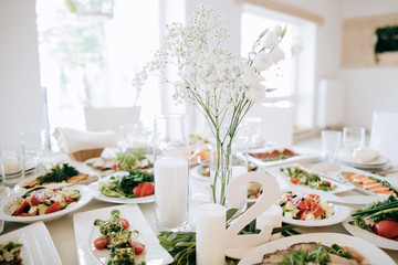 Wedding table decoration in white, food on the tables and flowers bouquets