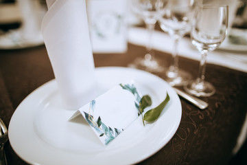 Festive table setting for dinner, name card for guests on the plate. Wedding idea