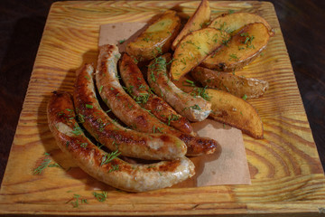 Rustic potatoes and fresh delicious fried chicken classic sausages. Close-up. Junk food.