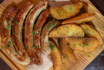 Rustic potatoes and fresh delicious fried chicken classic sausages. Close-up. Junk food.