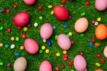 Colored eggs and vibrant candies on grass. Easter composition