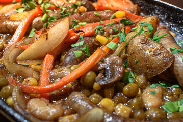 Hungarian frying pan (pork and beef sausages stewed with vegetables in dark beer) on a large wooden board. Tasty and healthy food. Close-up.