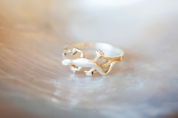 Sterling silver ring in shape of lizard on white shell background