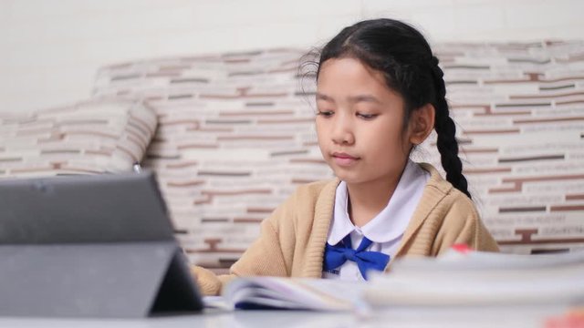 Little Asian girl doing homework with happiness, Thai girl in student kindergarten uniform, learning and education at home