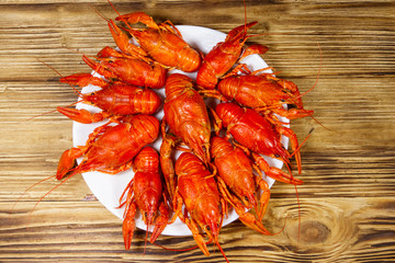Boiled crayfish in plate on wooden table. Top view