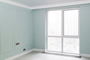 empty elegant mint colored room with boiserie on the walls and panoramic Windows with a convector in the floor