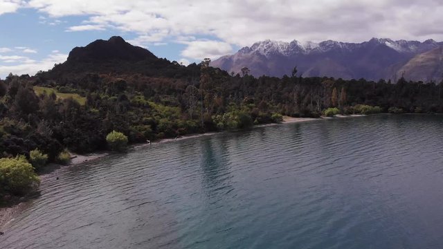 hills and blue lake rise up and reveal snowy mountains new zealand queenstown