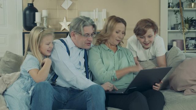 Little kids are having fun with a laptop and their grandparents