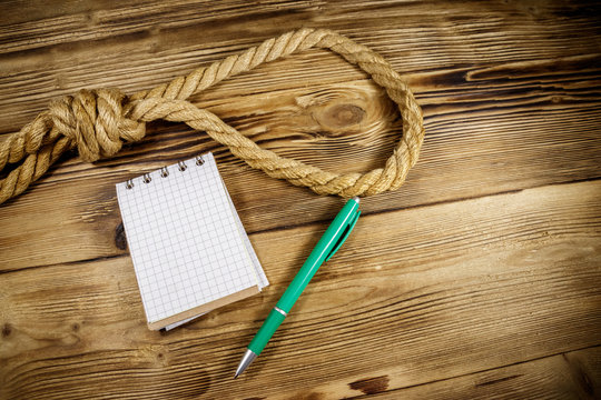 Deadly loop of rope and suicide note on a wooden background. Concept of suicide