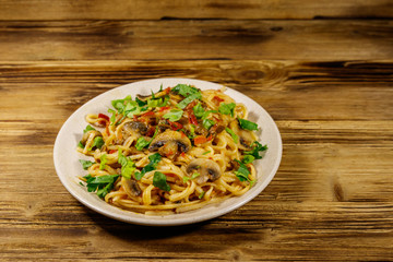 Pasta with mushrooms and tomato sauce on wooden table