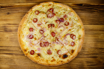 Delicious fresh pizza with sausage, red onion and cheese on a wooden table. Top view