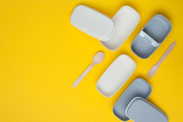 Empty plastic lunch boxes on yellow background with copy space