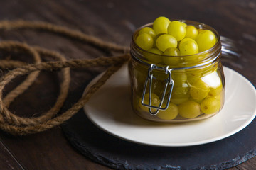 Jar of fresh grapes with handmade rope on an old basis