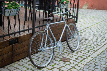 Fototapeta na wymiar Rear view of a white classic comfort bike parked on a fence in the streets of Loket, Czech Republic