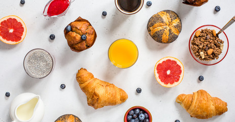 Modern continental breakfast, top view. Coffee, orange juice, milk, poppy seed buns, blueberry...