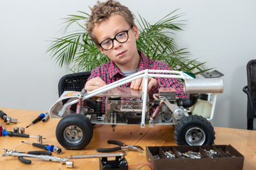 little boy repairing a model radio-controlled car at home